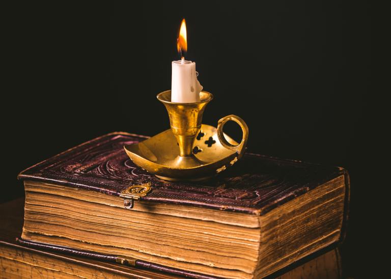 pile of old antique books with candle vintage style