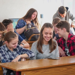 Elever vid sina bänkar i klassrum skrattar och ler tillsammans över något.