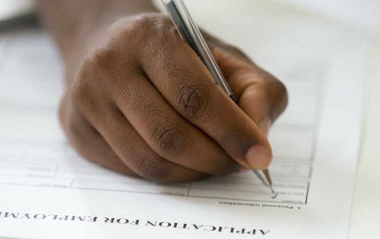  A dark-skinned hand filling in a job applicationa 