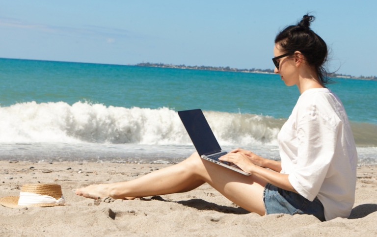 Student på stranden med laptop