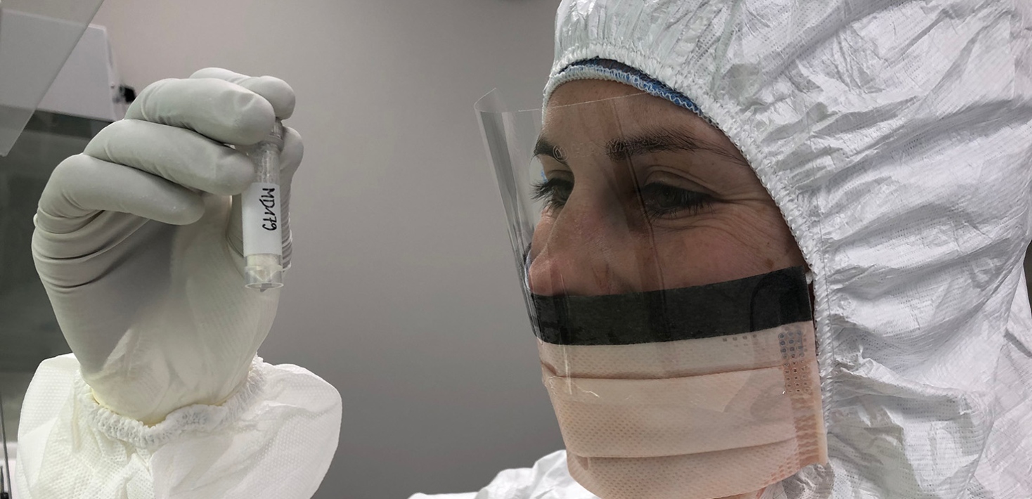 Researcher in protective clothing inspecting a tube
