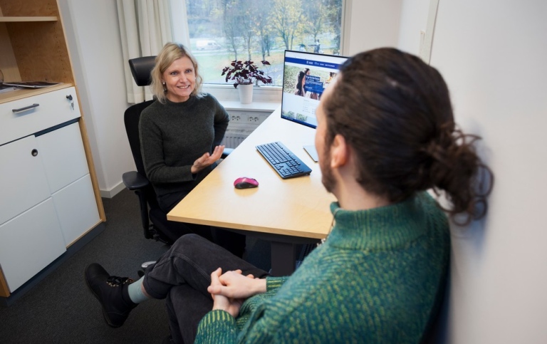 Studievägledare och student sitter och samtalar i ett rum.