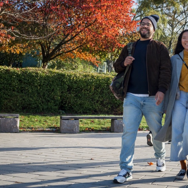 Two students walking on Campus, trees in autumn colours in the background. Photo: Jens Olof Lasthein