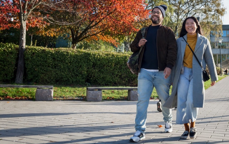 Two students walking on Campus, trees in autumn colours in the background. Photo: Jens Olof Lasthein