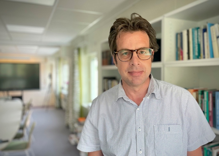 Kenneth Nelson, professor of sociology at Stockholm Univerity, in a big room with books and a tv