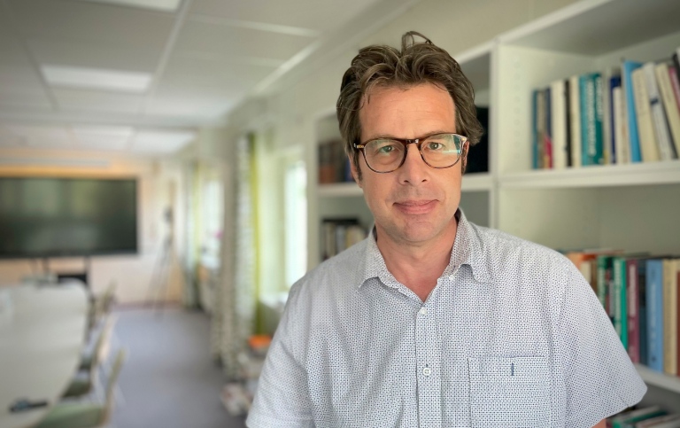 Kenneth Nelson, professor of sociology at Stockholm Univerity, in a big room with books and a tv