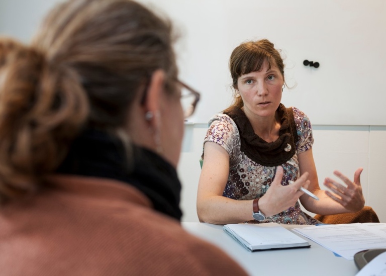 Två kollegor sitter vid ett bord och pratar.