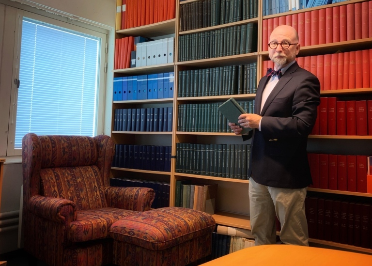 Johan Schelin står i Sjörättsbiblioteket med en bok i handen