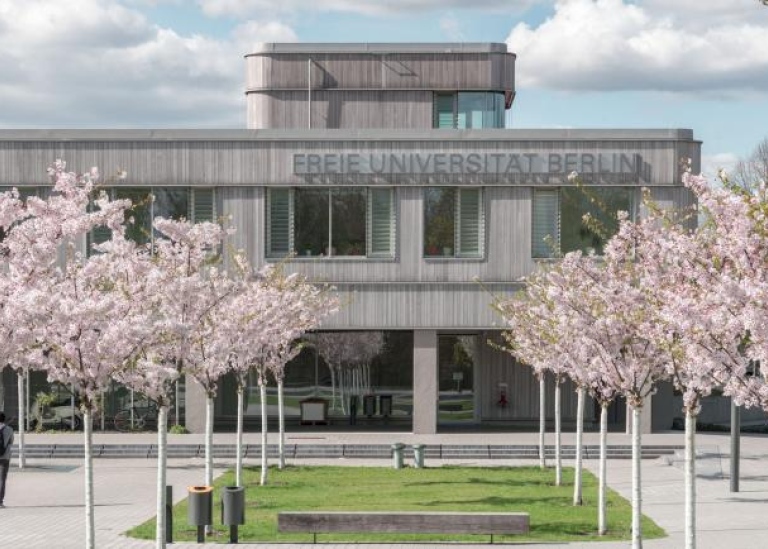 Universitetsbyggnad i brutalistisk stil med blommande körsbärsträd framför