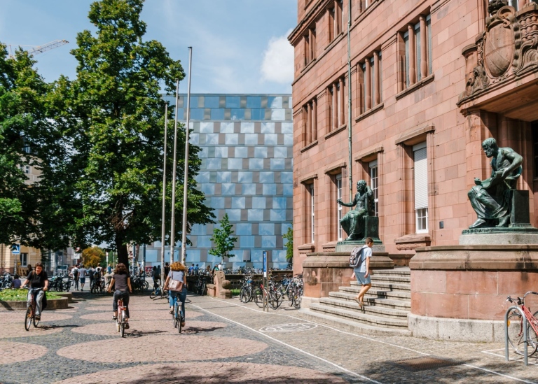 Universitetsbyggnad i Freiburg med cyklister och träd framför