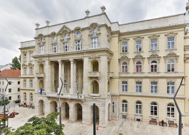 Gammal universitetsbyggnad med EU- och ungersk flagga.