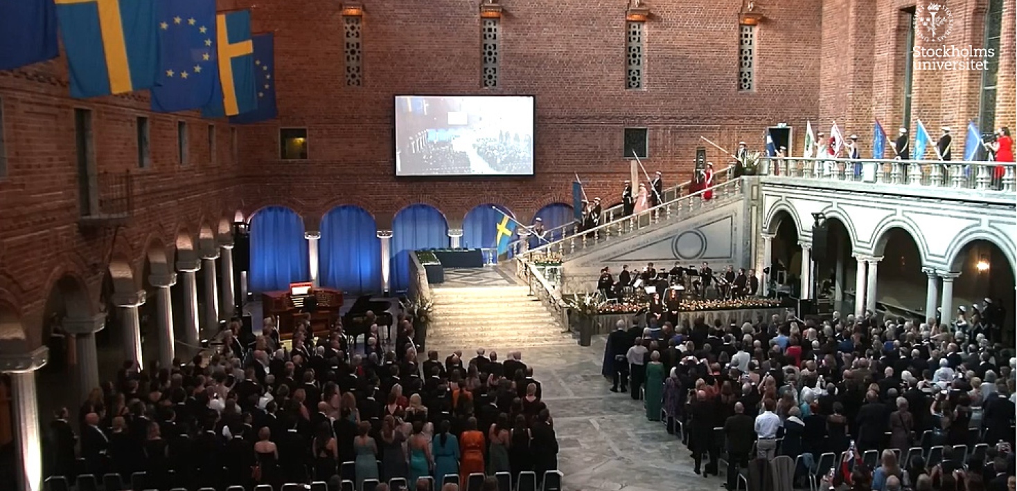 Fanbärarna går ned för trappan inför åhörare i Blå hallen i Stockholms stadshus.