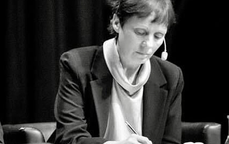 Elisabeth Geiger Poignant med hörlurar och mikrofon skriver i ett anteckningsblock.