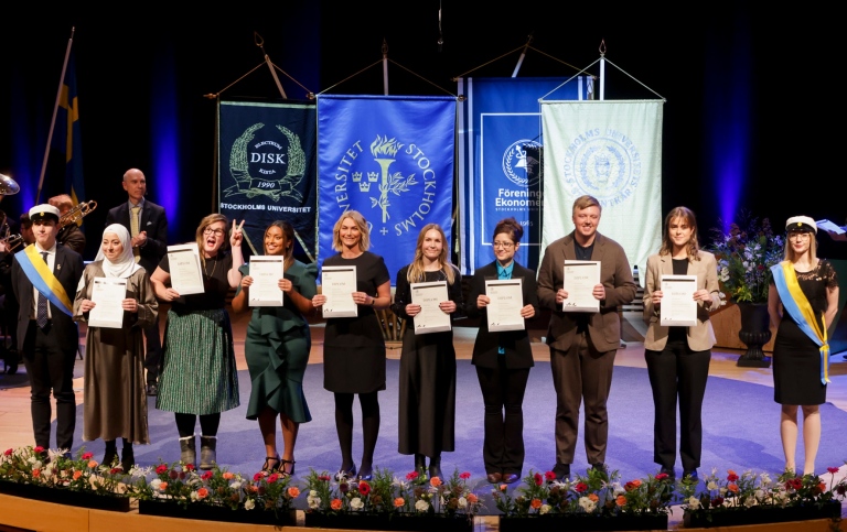 Eight masters with diplomas in their hands on stage in Aula Magna. Photo: Sören Andersson.