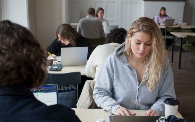 Blandade studenter sitter vid olika bord och studerar. 