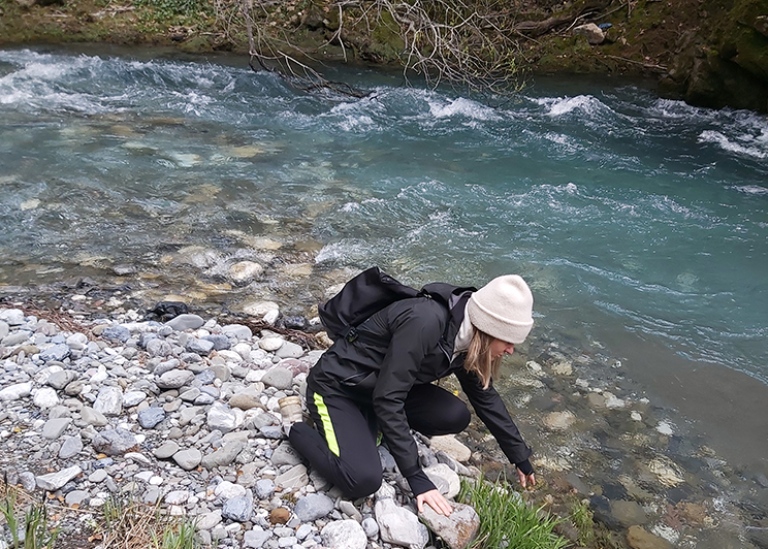 Student vid en flod och plockar med något i vattnet