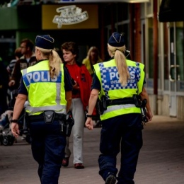 Two police officers walking away towards a crowd of people.