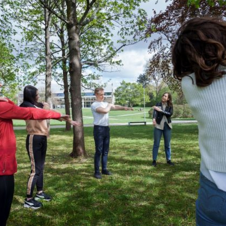 Studenter utövar medicinsk yoga utomhus.