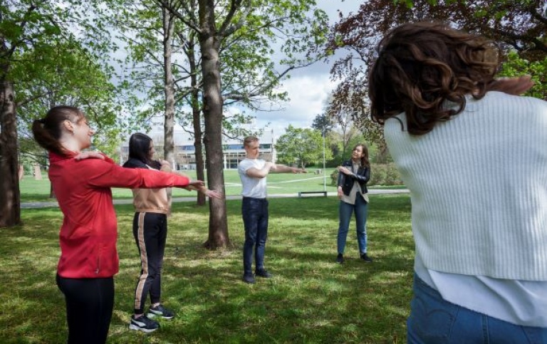 Studenter utövar medicinsk yoga utomhus.