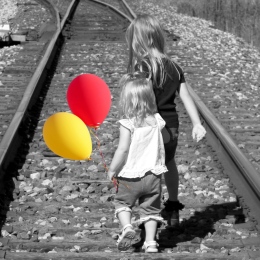Barn på järnvägsspår med ballonger