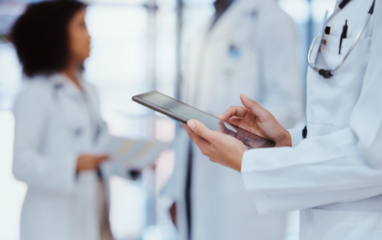 Three medical doctors, one holding an Ipad.