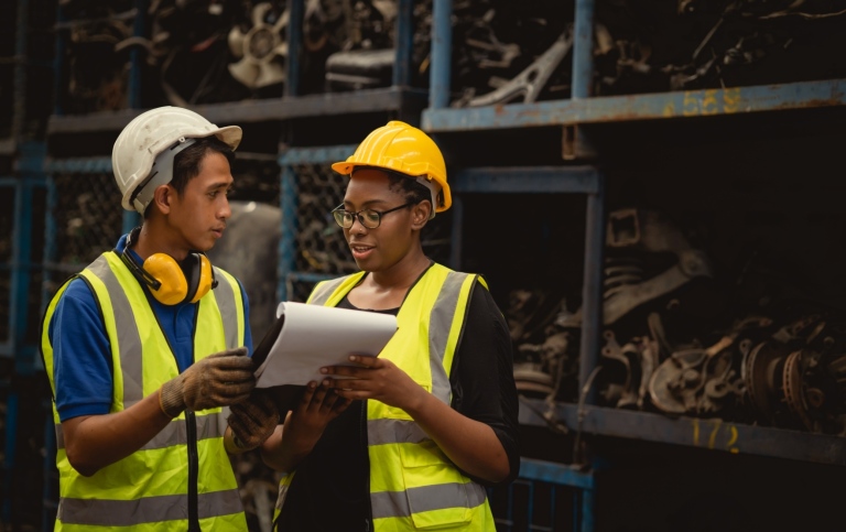 Man and woman workers, dark skinned, with helmets and vests