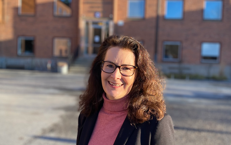 Malin Luterkort står utanför en tegelbyggnad, en av ingångarna till institutionen