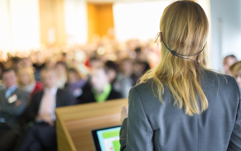 Kvinna som står som talare på en konferens