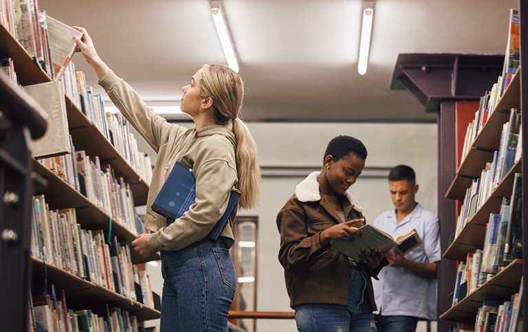 Tre studenter på ett bibliotek