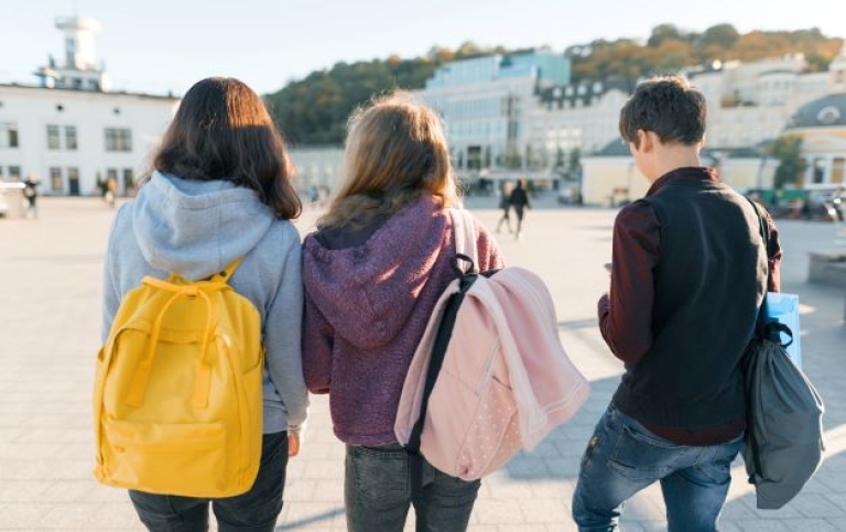Elever med ryggsäckar på en skolgård.