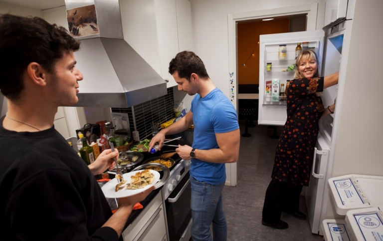 Students cooking together in kitchen in a student housing. 