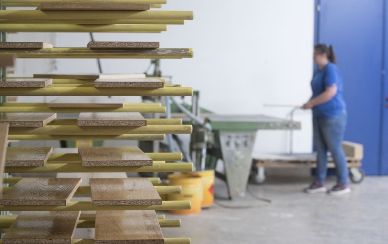 Woman standing beside wooden boards drying after wood gluing at the joinery or carpentry 