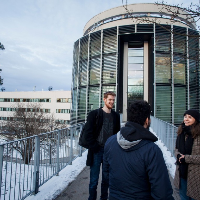 Tre personer står farmför entren till Albanova universitetscentrum