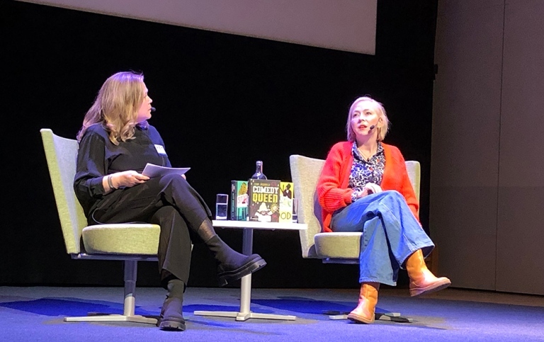 Two persons sitting on stage talking