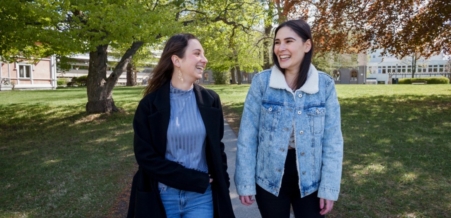 Två leende kvinnliga studenter går ute på Frescati campus. 