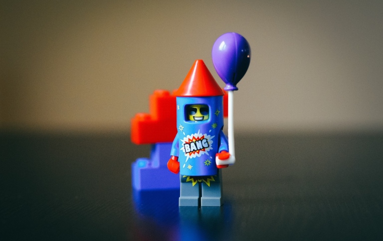 Legogubbe som ser ut som en raket med en ballong i handen