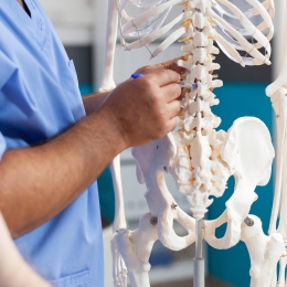 Bild på sjuksköterska som pekar med penna på ett skelett.