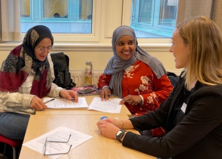 Två sfi-elever samtalar med en lärare