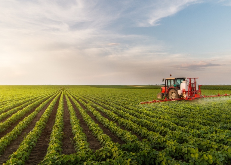 Tractor spraying pesticides at soy bean field