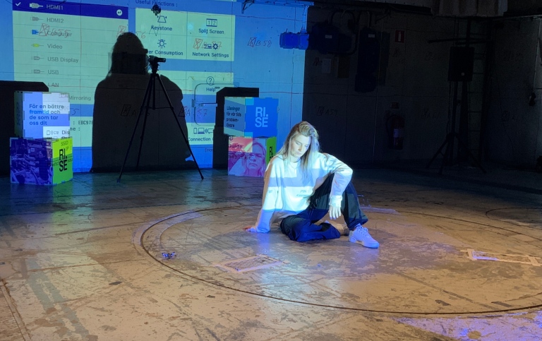 DSV student Hanna Dahl sitting on a stage with a drone, performance in 2nd Drone Arena Challenge.