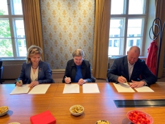 Three persons signing papers.