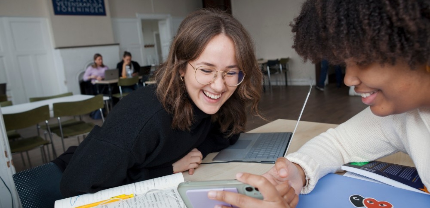 Two female students laughing together during their study session.