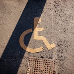 A handicapped sign painted on the asphalt of a parking lot