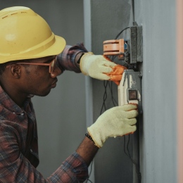 Man in hat holding black and gray power tool