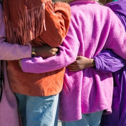 Four women holding each others' waist at daytime