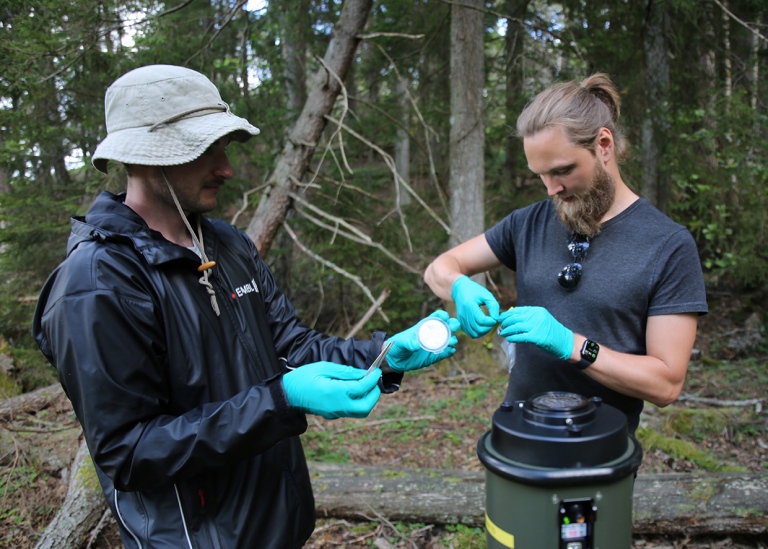Två deltagare tar luftprover i skogen på Askö.