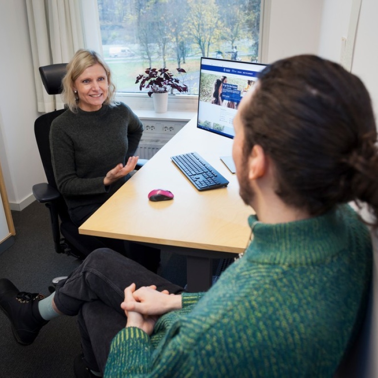 Två personer sitter och samtalar i ett rum.