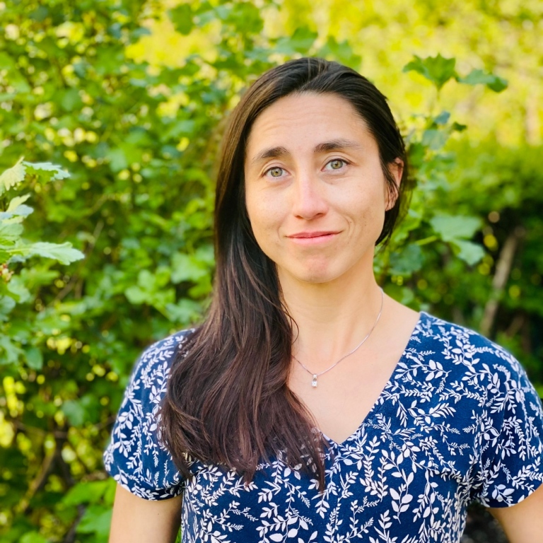 Elisa Viteri in front of some greenery.