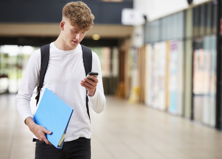 En ung kille tittar på sin mobiltelefon.