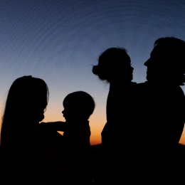 Silhouette of a family standing during sunset